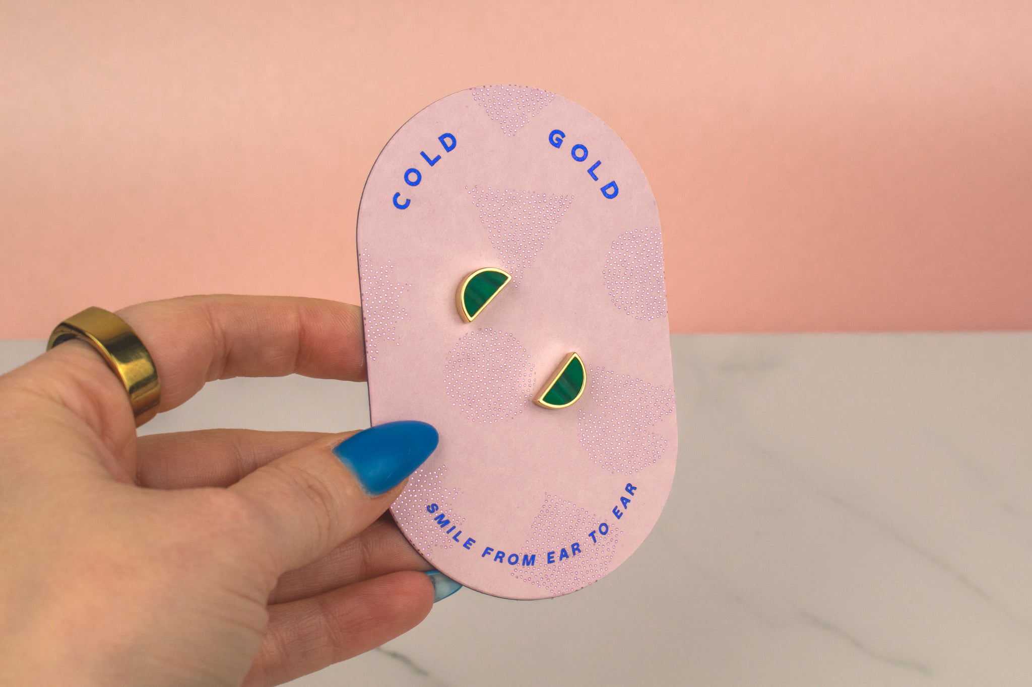 pink geometric card showing a pair of emerald studs with 14k gold plated moon stud earrings on a white background, great for September birthstone gift