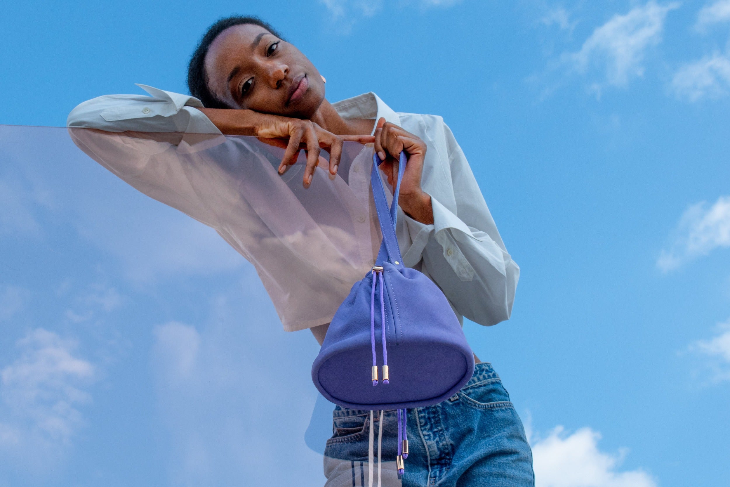 model leaning on piece of colored acrylic displaying purple nubuck bucket bag