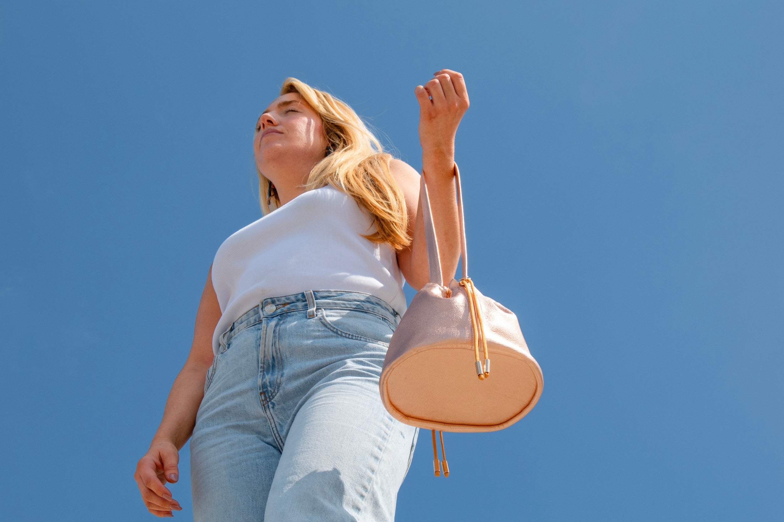 model blue sky background rose gold wristlet pouch bag drawstring closure with gold hardware