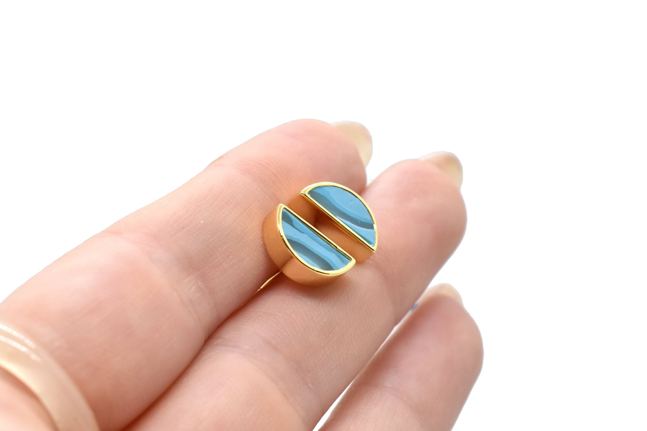 hands holding a pair of  geometric triangle stud earrings in aqua blue birthstone gemstone close up