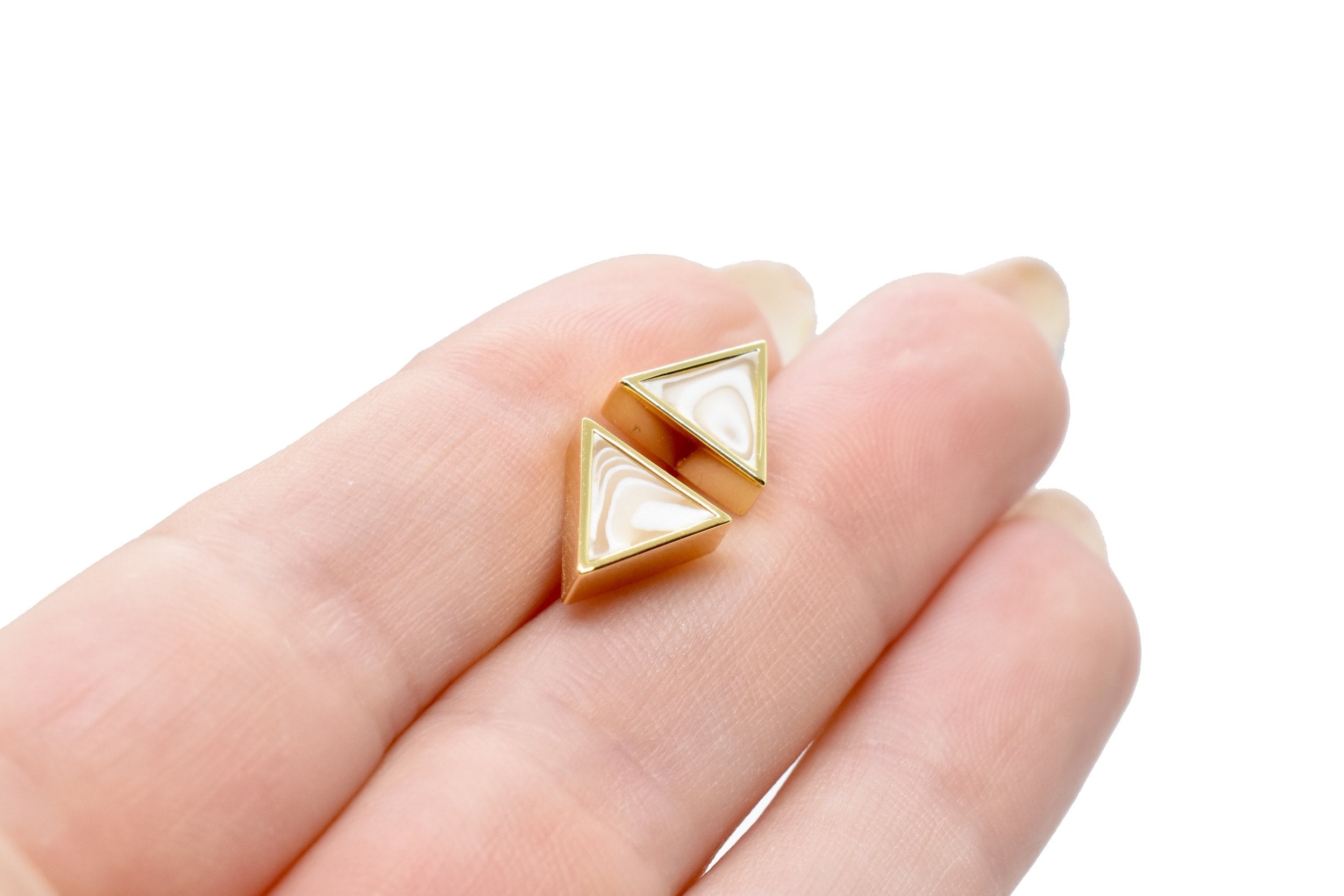 hand holding gold geometric triangle stud earrings white quartz gemstone earrings