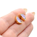 hand holding a pair of celestial gold stud earrings in amethyst marble