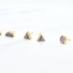three pairs of modern and minimal pastel purple earrings in three shapes: hexagon studs, triangle studs, and half-moon studs with gold details.