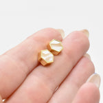 hand holding modern and minimal hexagon stud earrings in vanilla crystal quartz and gold
