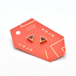 red geometric card with ruby studs in a 24k gold triangle shape, geometric jewelry made for sensitive ears shown with ruby pattern and watercolor texture