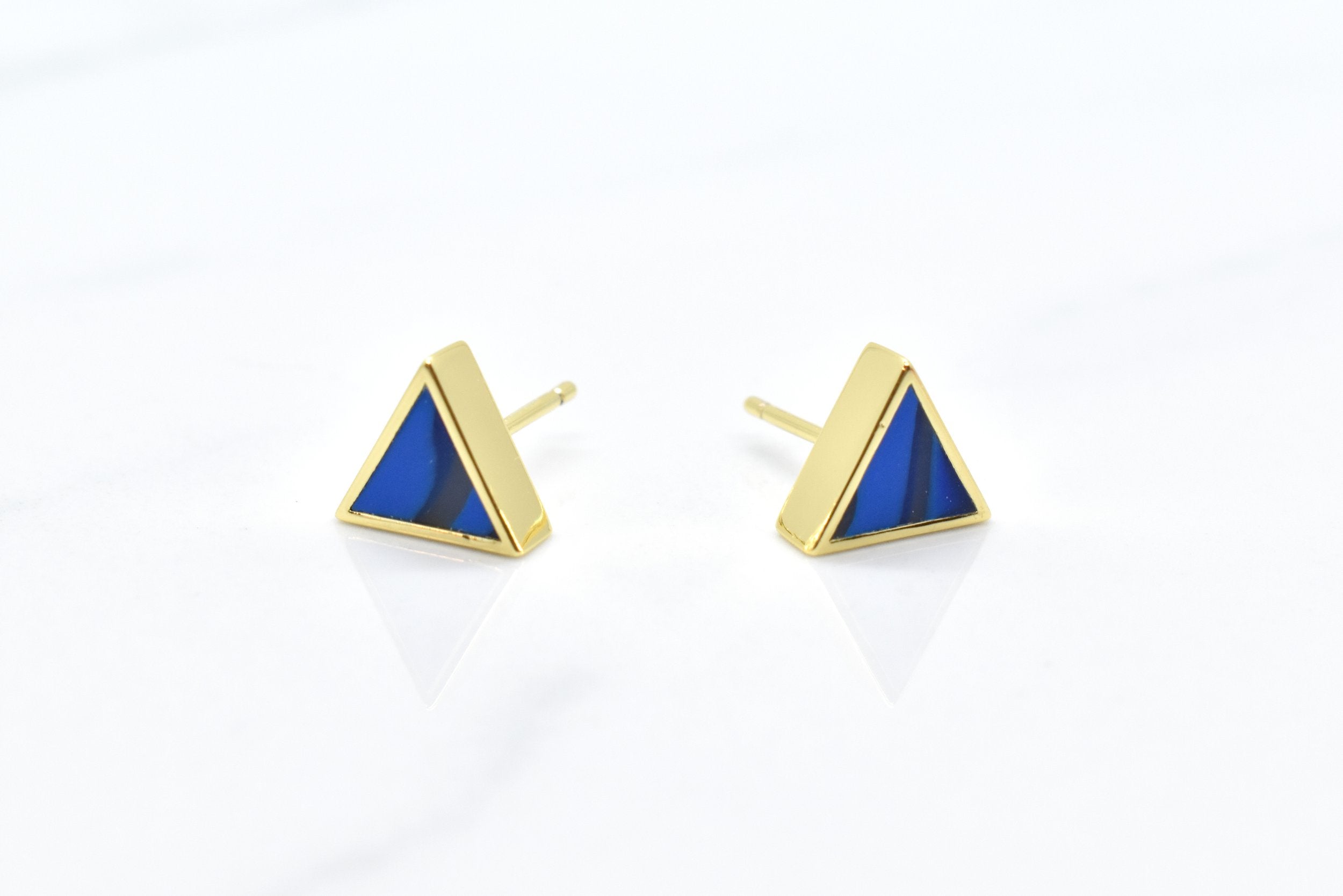 gold triangle stud earring set in sapphire gemstone like clay against a white background
