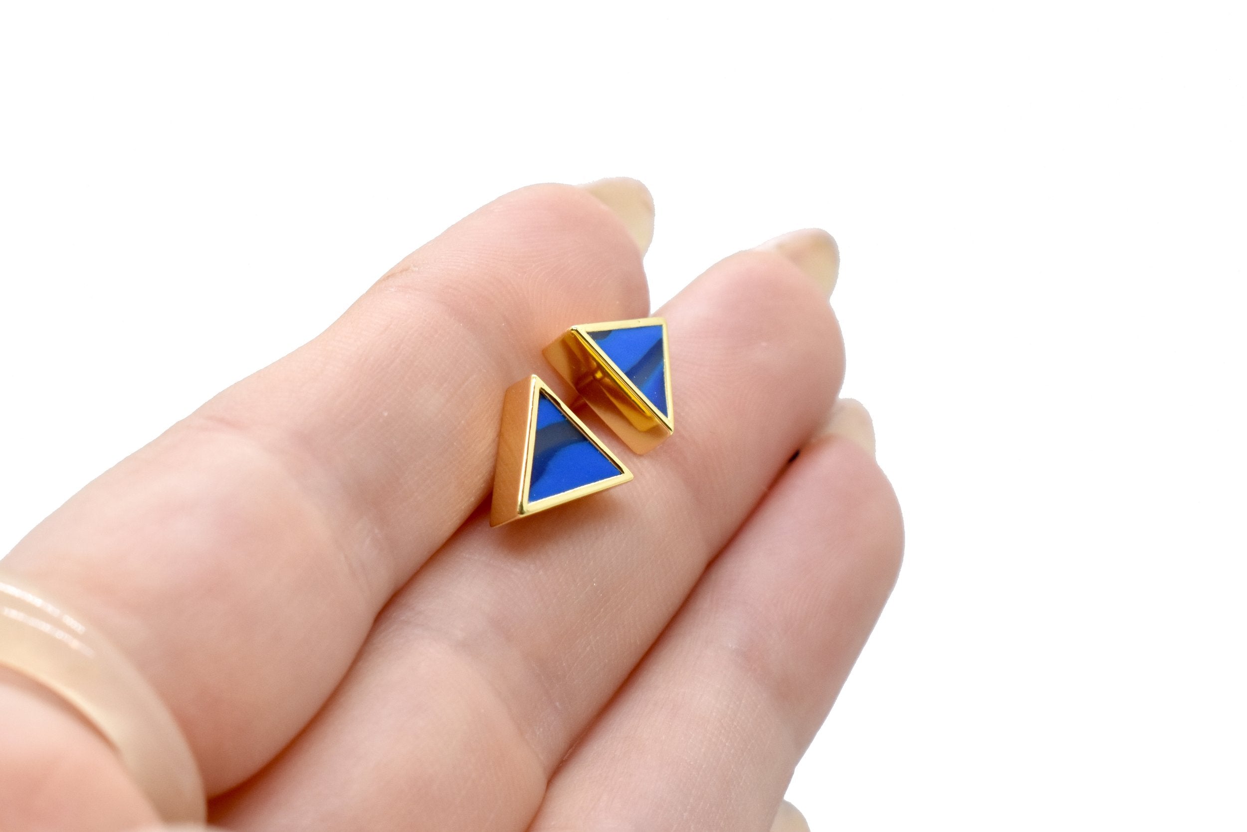 hands holding a pair of geometric triangle stud earrings in matisse blue with gemstone texture clay, hand marbled to look like sapphire, a perfect gift for a September birthday