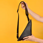 shown being held, a black triangle small leather bag, black adjustable strap for all body types
