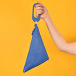 a hand holding a wristlet clutch version of the blue sling bag cute sling in matisse blue perfect for beach trip