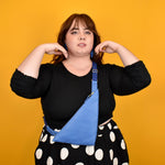 person wearing blue leather bag sling triangle shaped purse