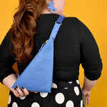 person shown from the back wearing a leather sling tote that holds their cell phone with adjustable strap for all body types