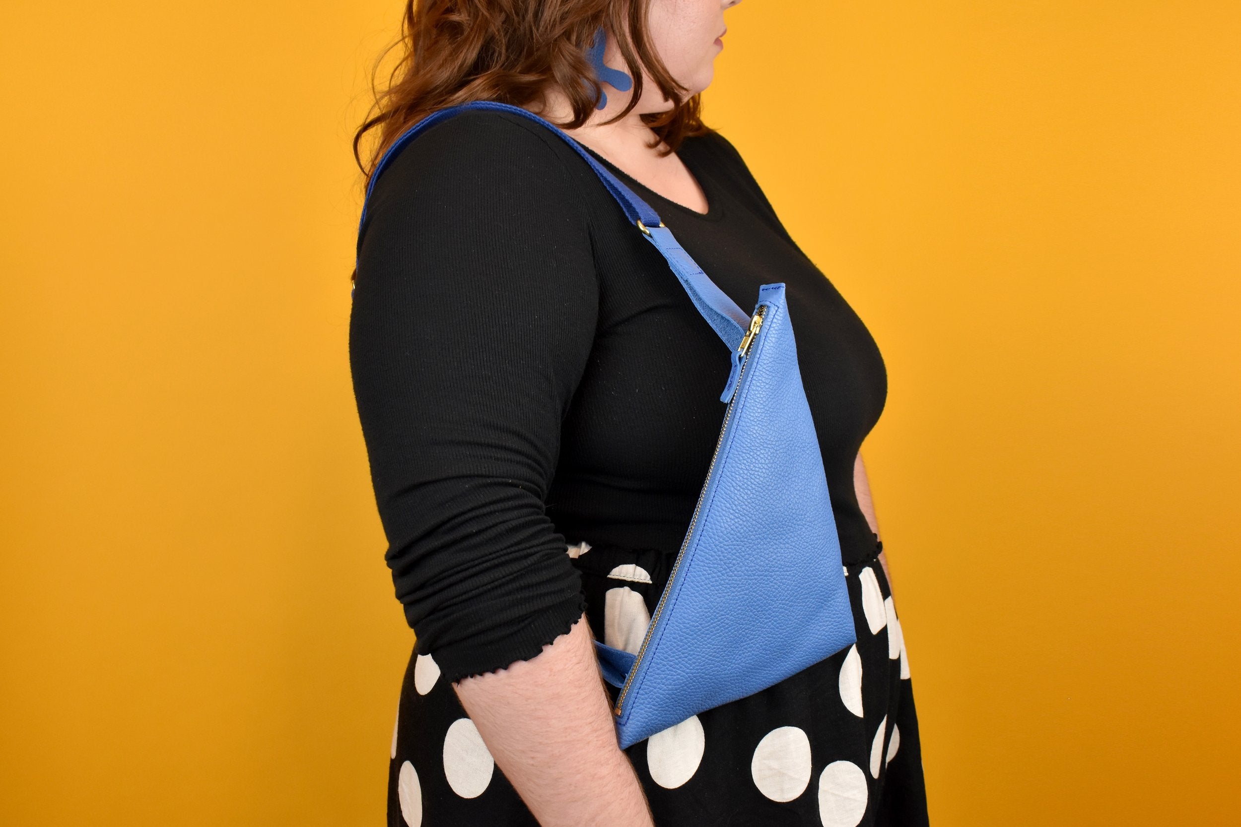 a person shown from the side with a sling bag in matisse aesthetic blue pop of color bag colorful sling for outdoor adventures