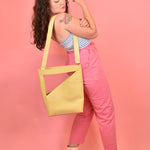 pale yellow crossbody bucket bag hanging off shoulder