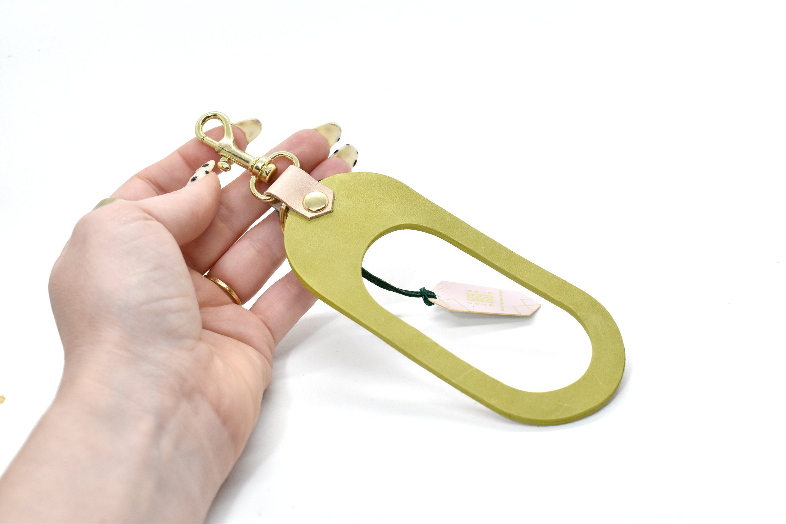 A vegetable tanned rawhide and bright lime green leather finish keychain with gold hardware