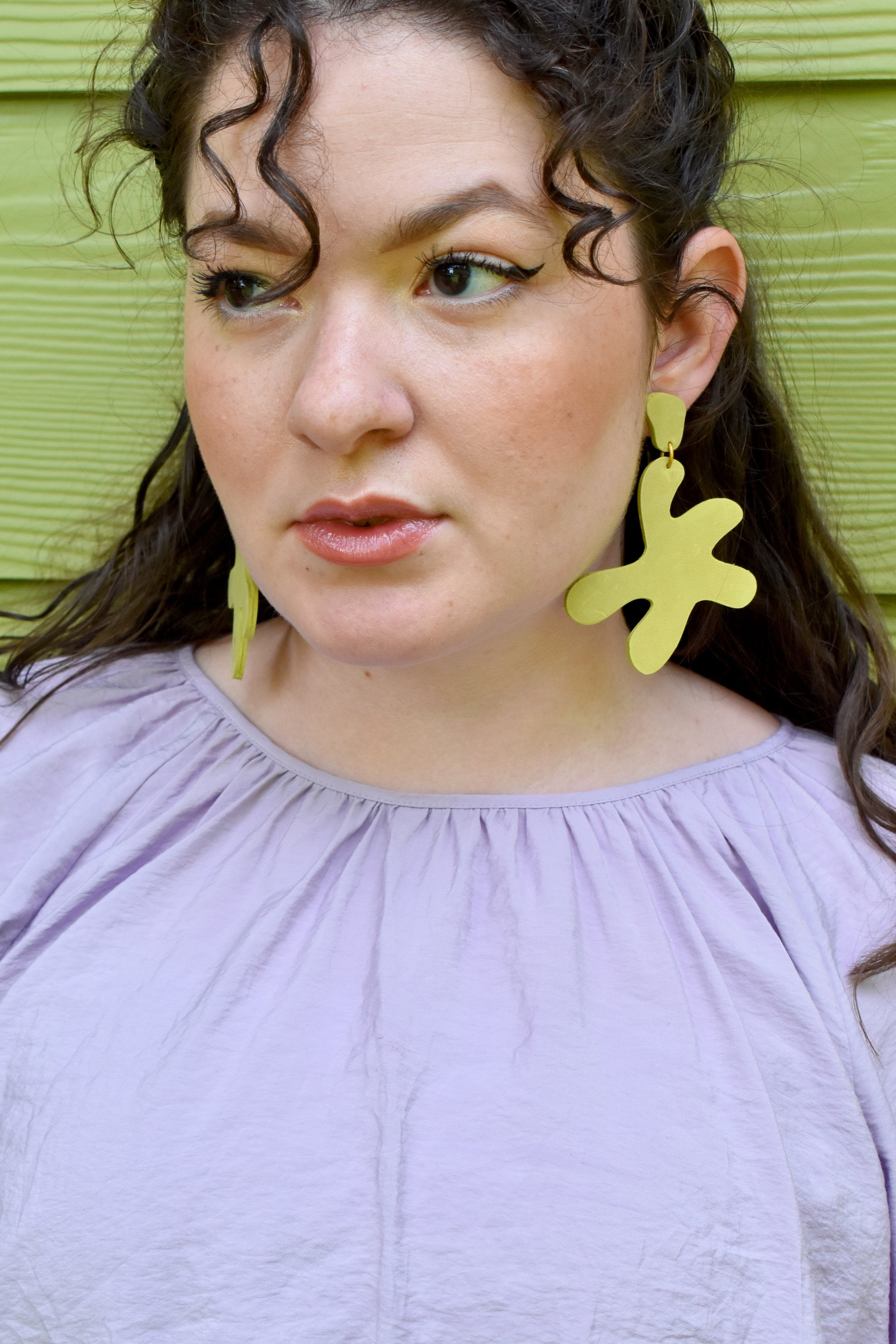 lime green matisse inspired leather statement earrings on a young woman