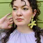 bold and modern lime green leather earrings in chartreuse on a woman with long curly dark hair.