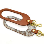 A dual color leather keychain, hand riveted with gold plated brass keyring and clasp, featuring speckled hair on hide and chestnut leathers.