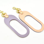 A dual-sided leather multicolor keychain in veg tan leather and matte pastel purple leather.