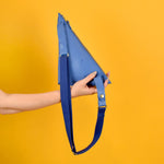a hand holding a lightweight bag triangle shape accessory with a long strap perfect for music festivals like coachella bag