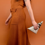 a woman carries a speckle black leather sling bag for music festival essentials bag small leather crossbody purse clutch hair on hide leather cowgirl accessories for bachelorette party in her hand