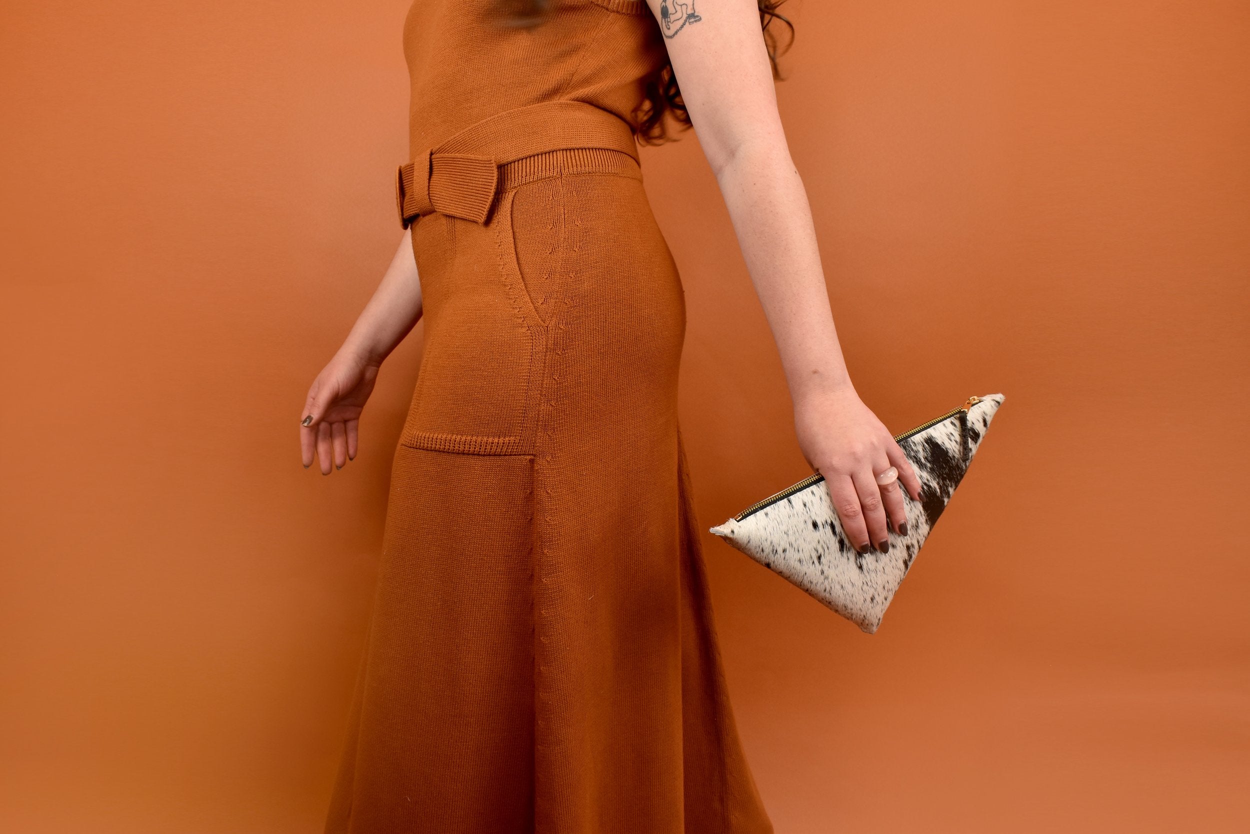 a woman carries a speckle black leather sling bag for music festival essentials bag small leather crossbody purse clutch hair on hide leather cowgirl accessories for bachelorette party in her hand