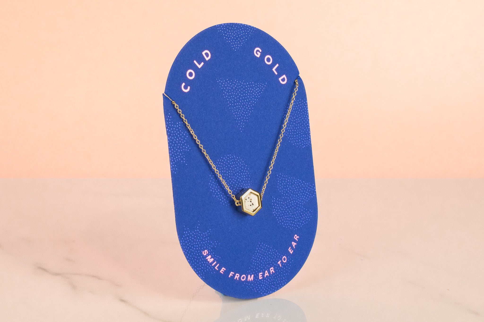 polka dot terrazzo necklaced displayed on blue cold gold branded jewelry card that says smile from ear to ear