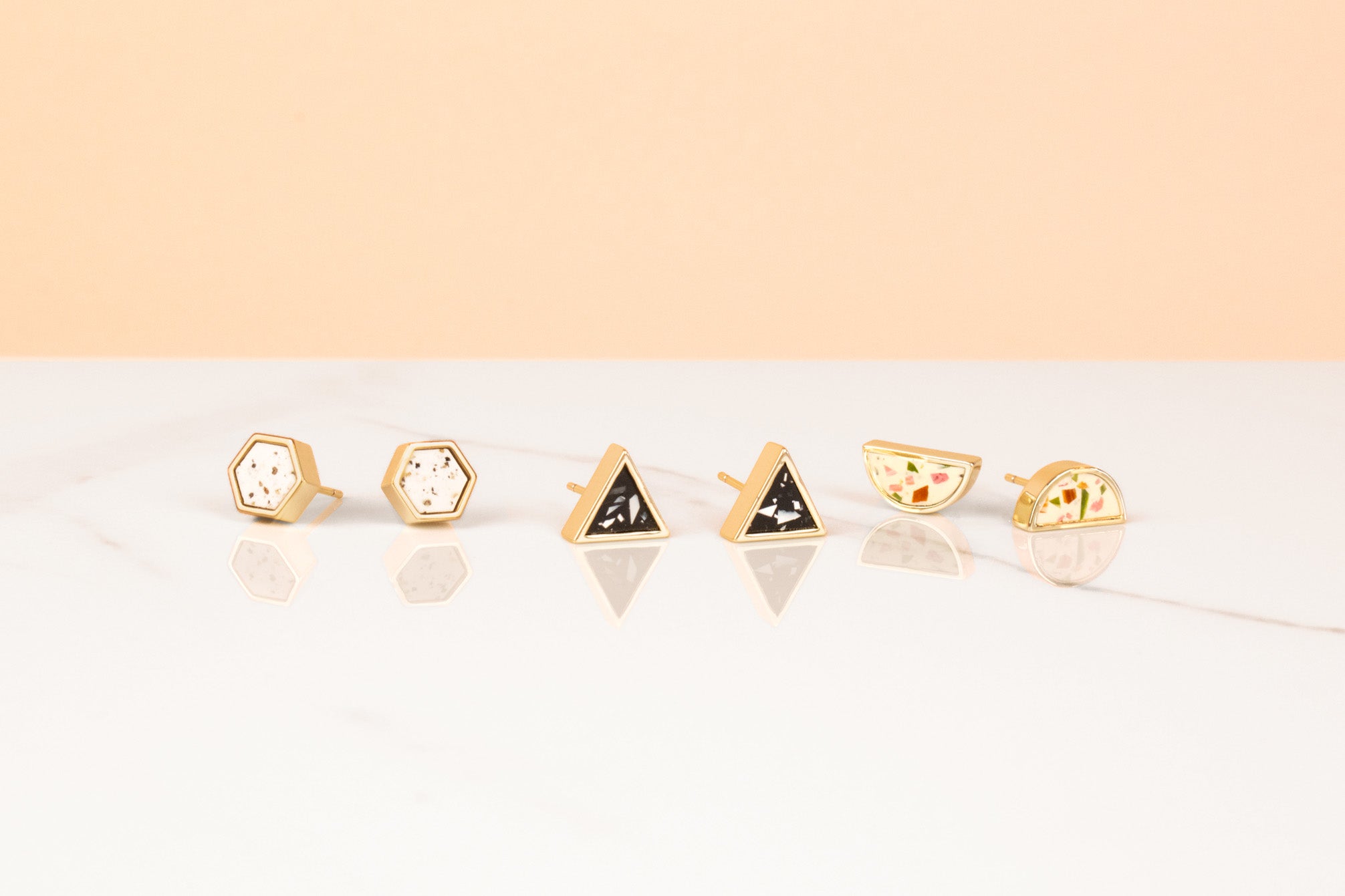 geo studs collection in three new colorways lined up: dalmatian hexagon, night sky terrazzo triangle, jewel tone half moon terrazzo