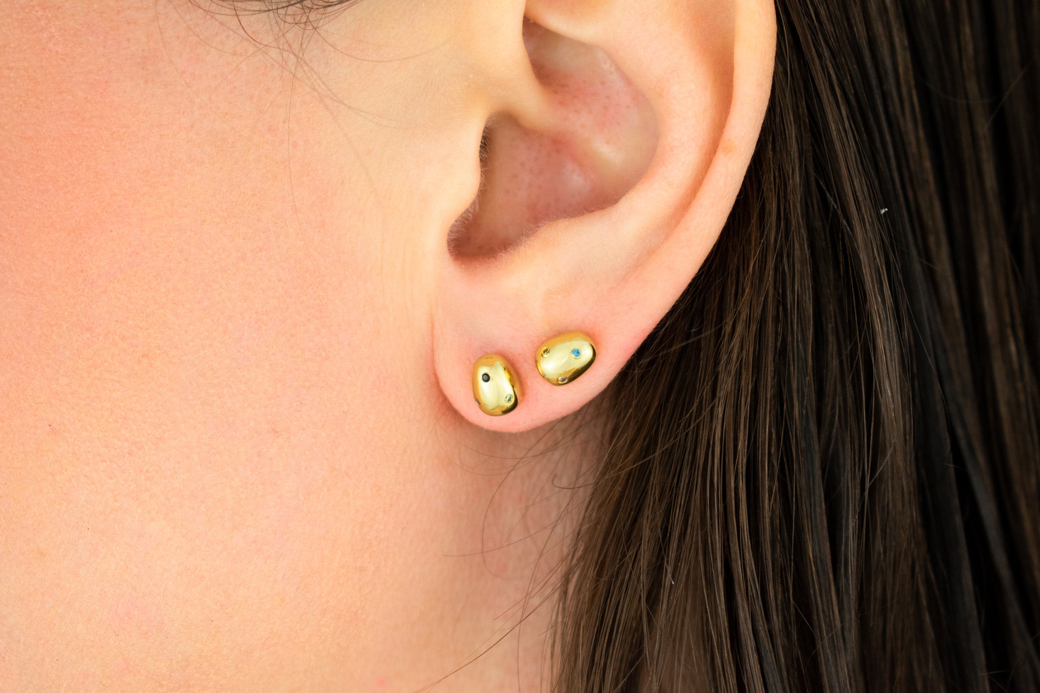 model with double lobe piercing wearing 14k gold plated baroque pearl studs encrusted with colorful CZ microgemstones