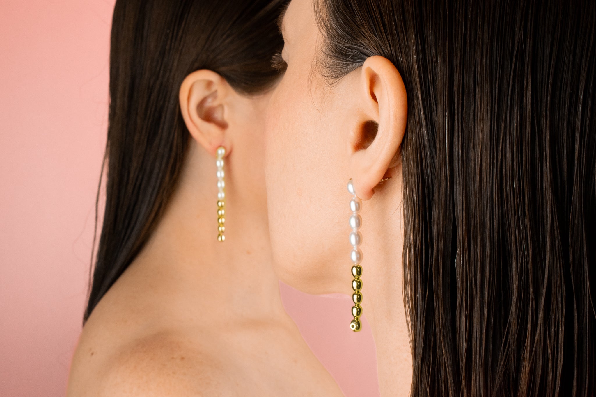 twin models facing away from camera wearing string of pearl earrings