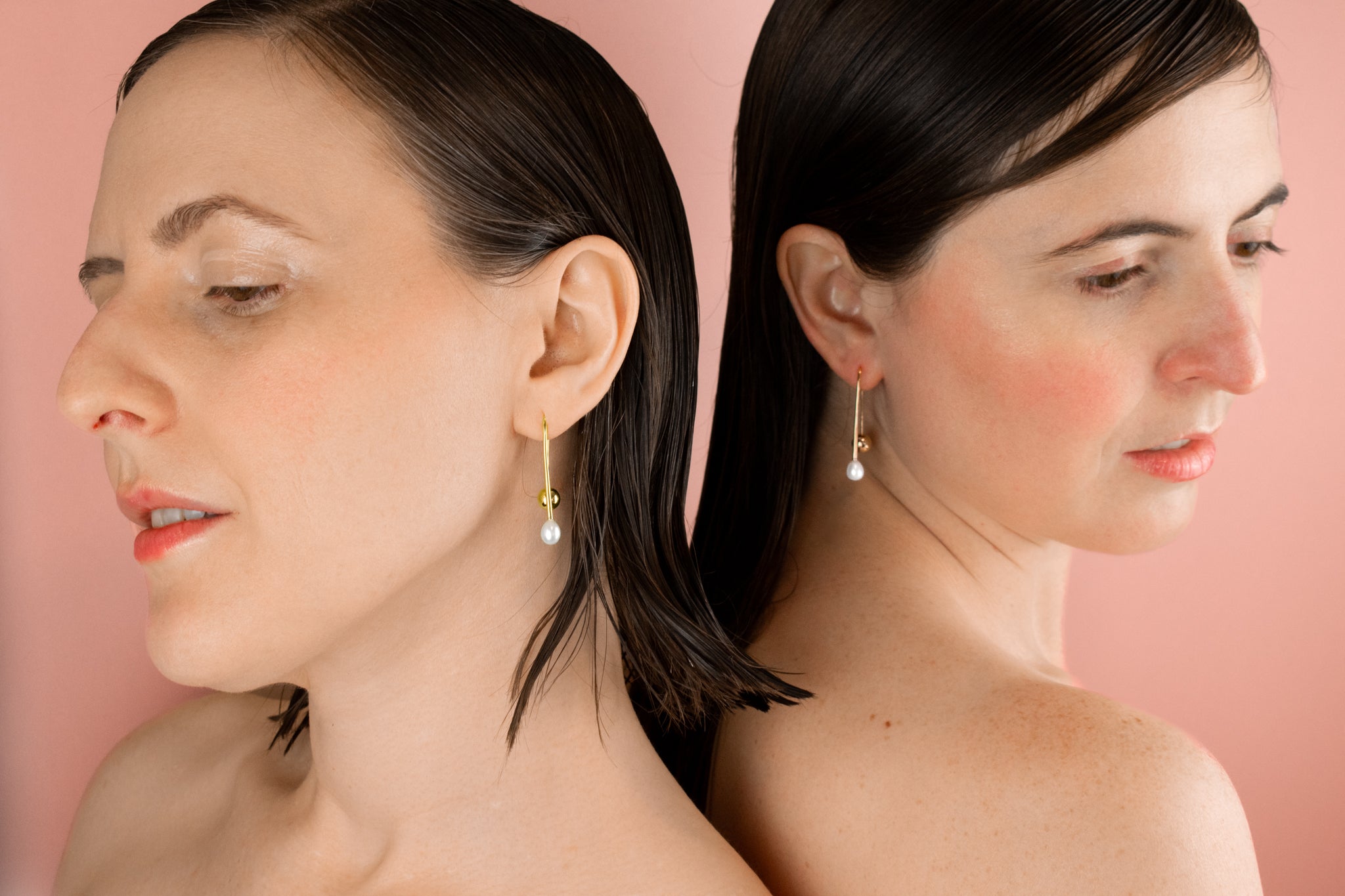twin models wearing delicate gold open hoop ear wire adorned with single baroque freshwater pearl