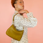 model pictured with green genuine leather handbag slung over shoulder