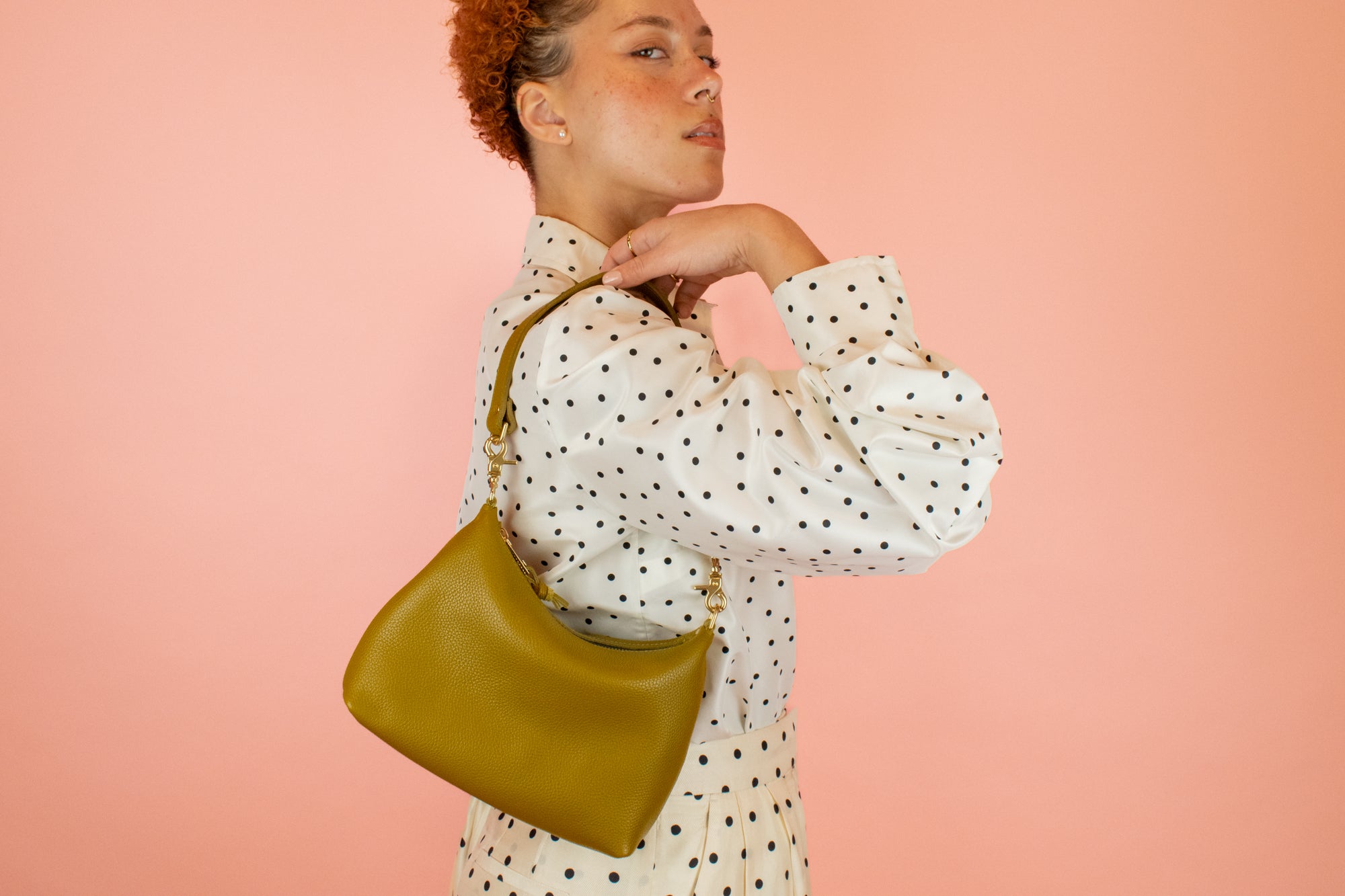 model pictured with green genuine leather handbag slung over shoulder