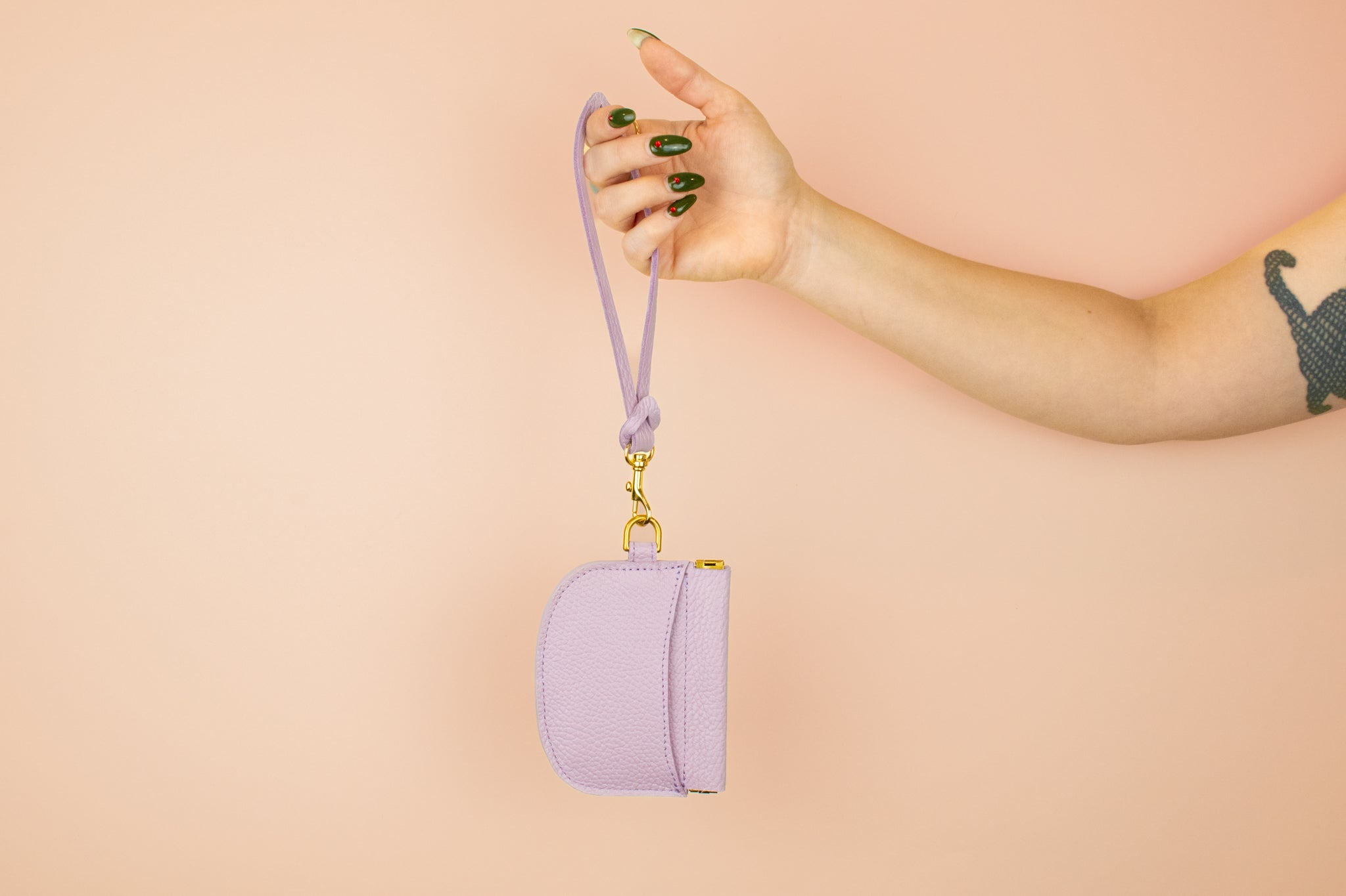 models arm holding up lilac loop keychain wristlet attached to matching leather card wallet with exterior pocket