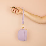 model displaying leather keychain slipped over her wrist attached to matching modern leather card holder in pale purple
