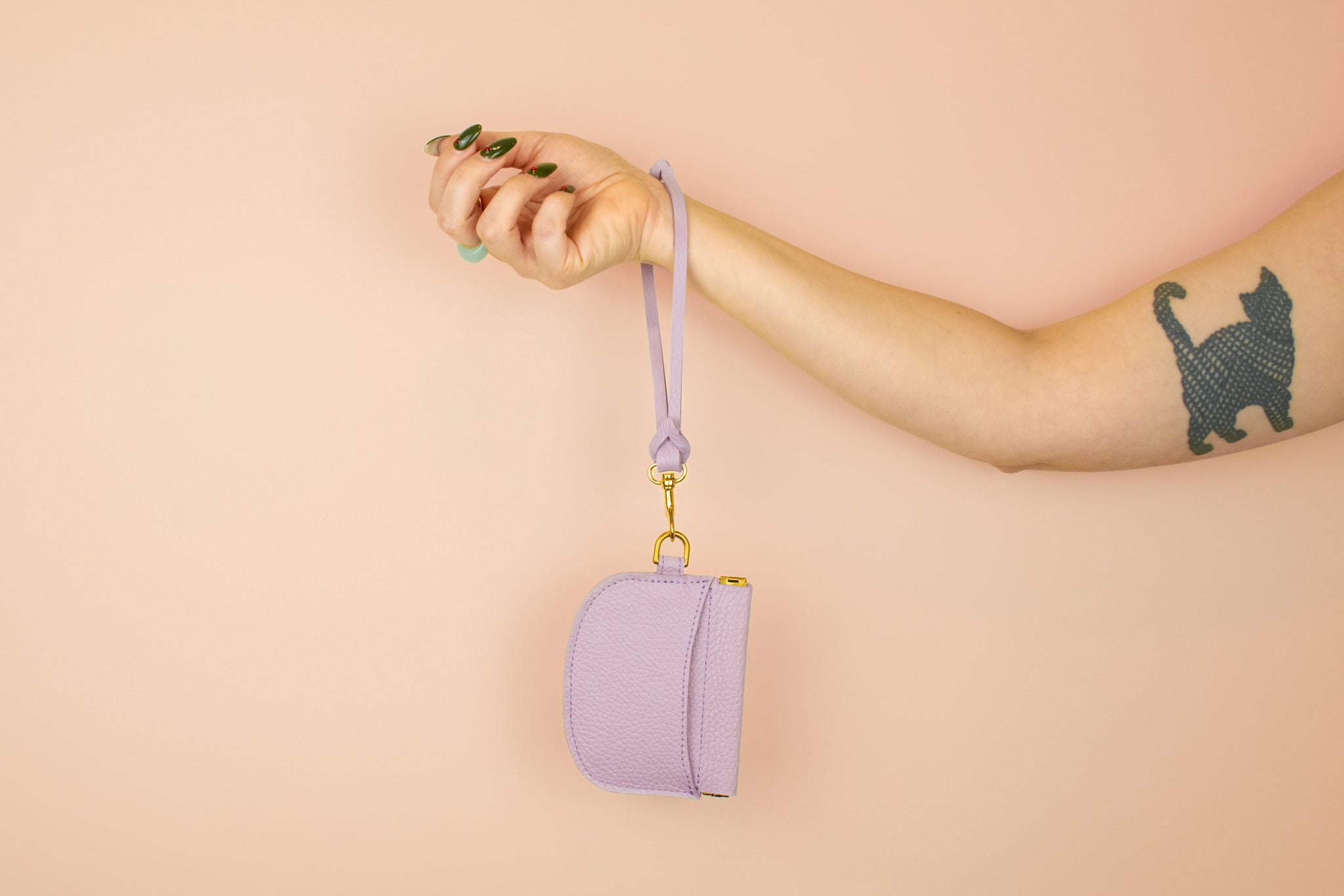 model displaying leather keychain slipped over her wrist attached to matching modern leather card holder in pale purple
