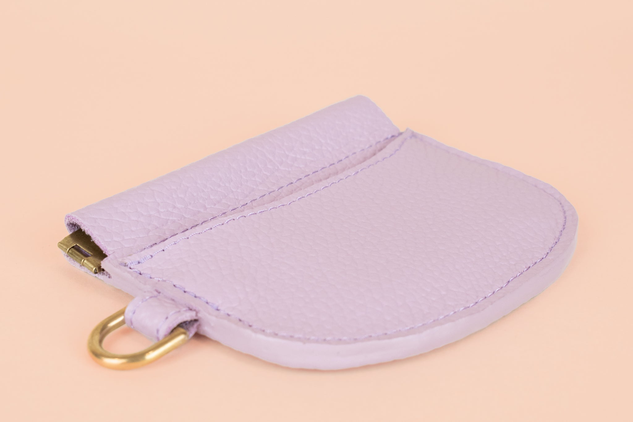 modern leather card holder lying flat to display slim sides featuring gold hardware for attaching keys and snap closure