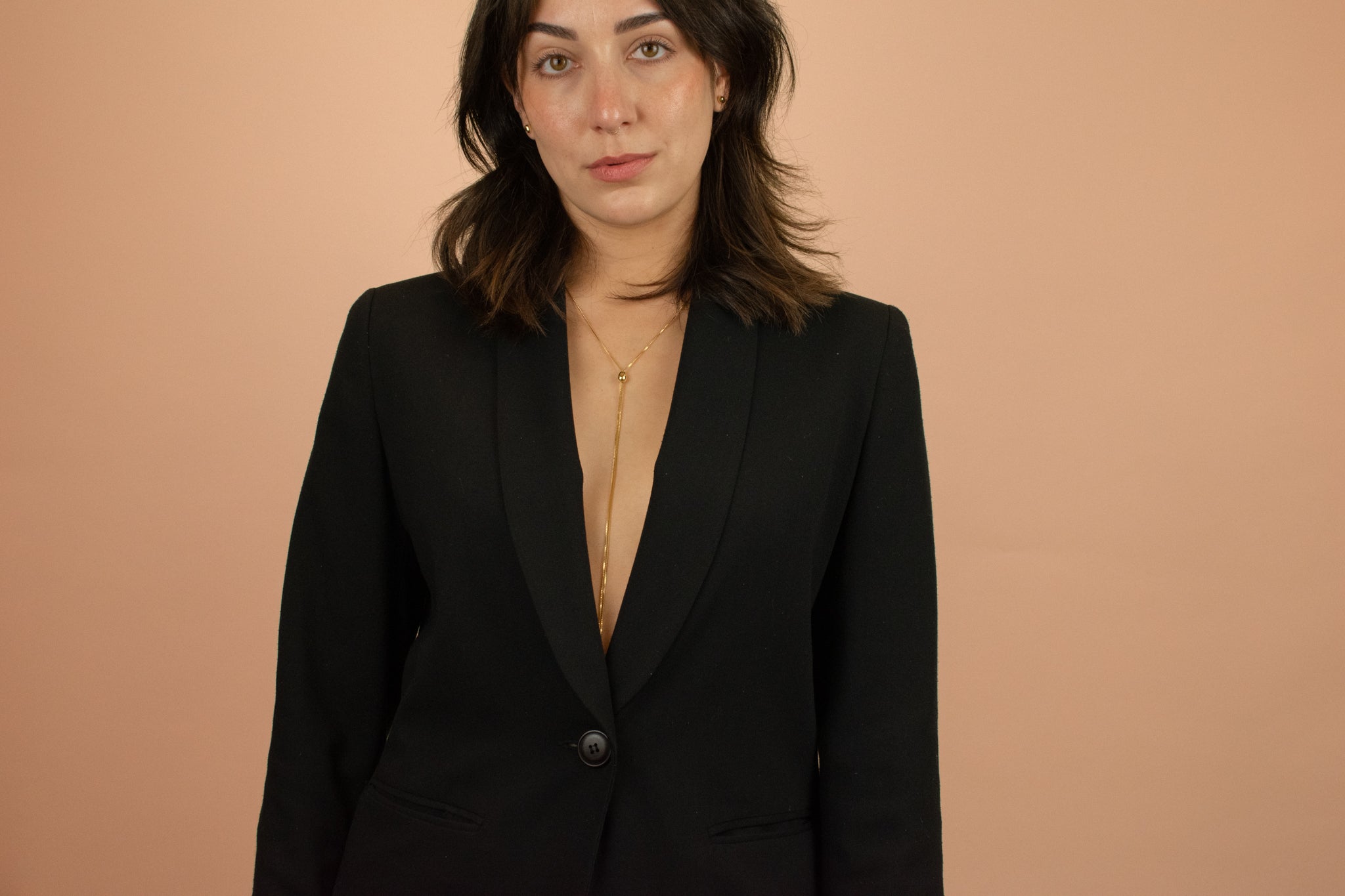 model in a black blazer wearing long gold modern adjustable bolo chain necklace
