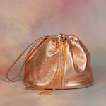 metallic rose gold leather ruched drawstring handbag with gold hardware