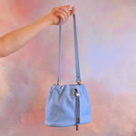 outstretched hand carrying light blue scrunchie bag