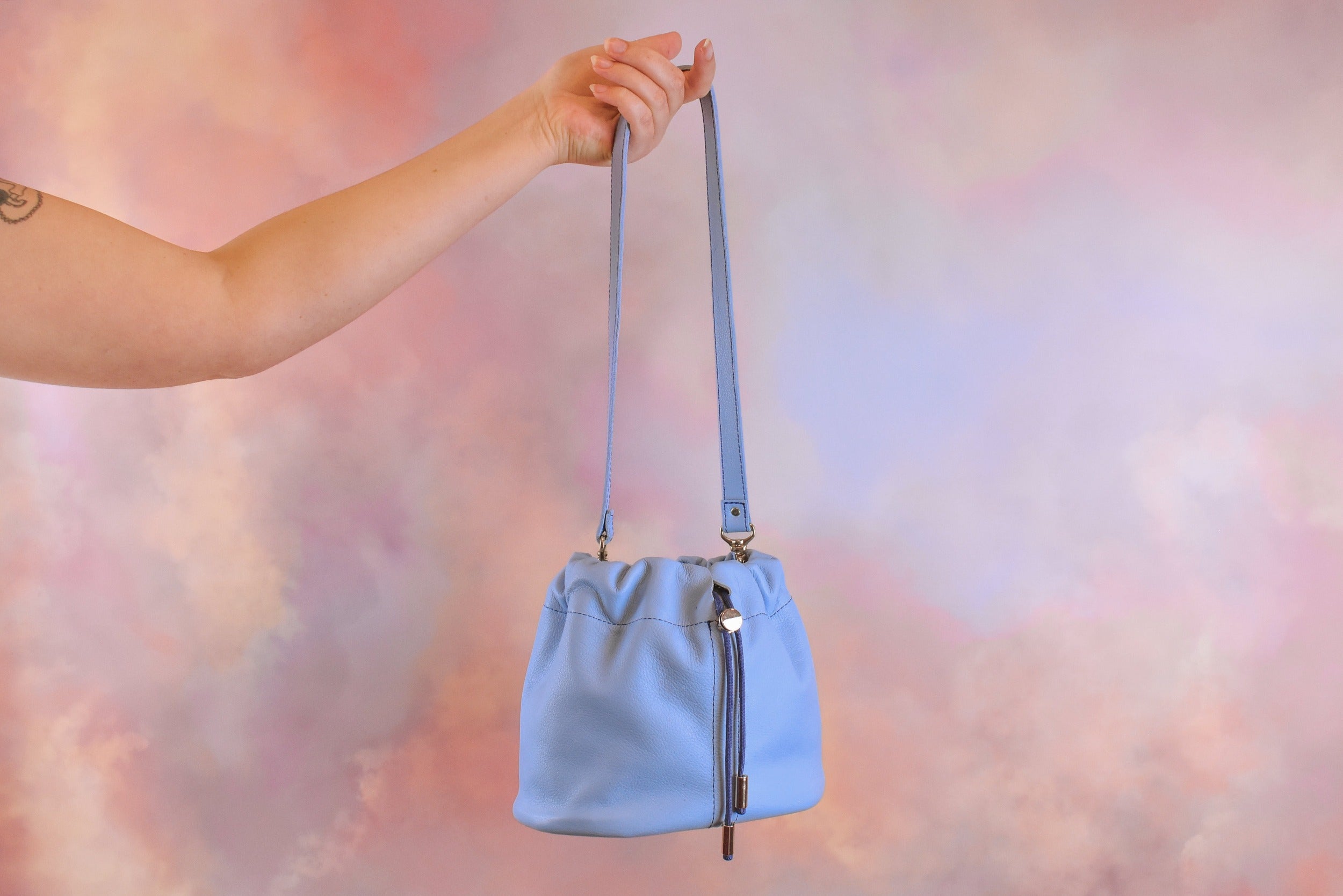 outstretched hand carrying light blue scrunchie bag