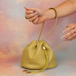 confetti manicured hands displaying yellow green leather scrunch top bucker bag