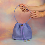 glitter manicured hands displaying light purple soft nubuck mini scrunch leather shoulder bag
