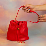 manicured hands displaying bright red luxury leather bucket bag drawstring closure gift for sister