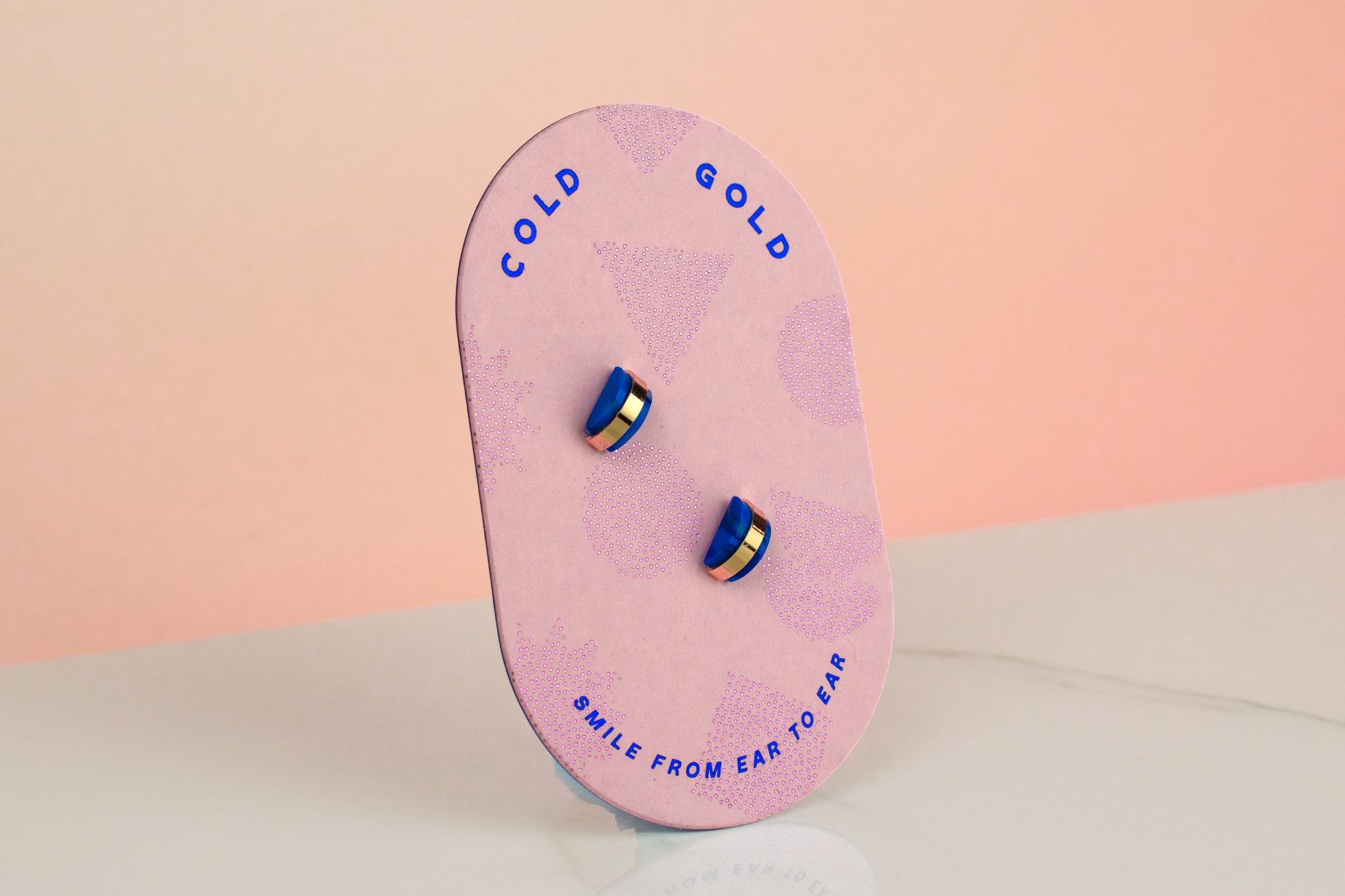 pink card displaying blue sapphire handmade gold hoop stud earrings