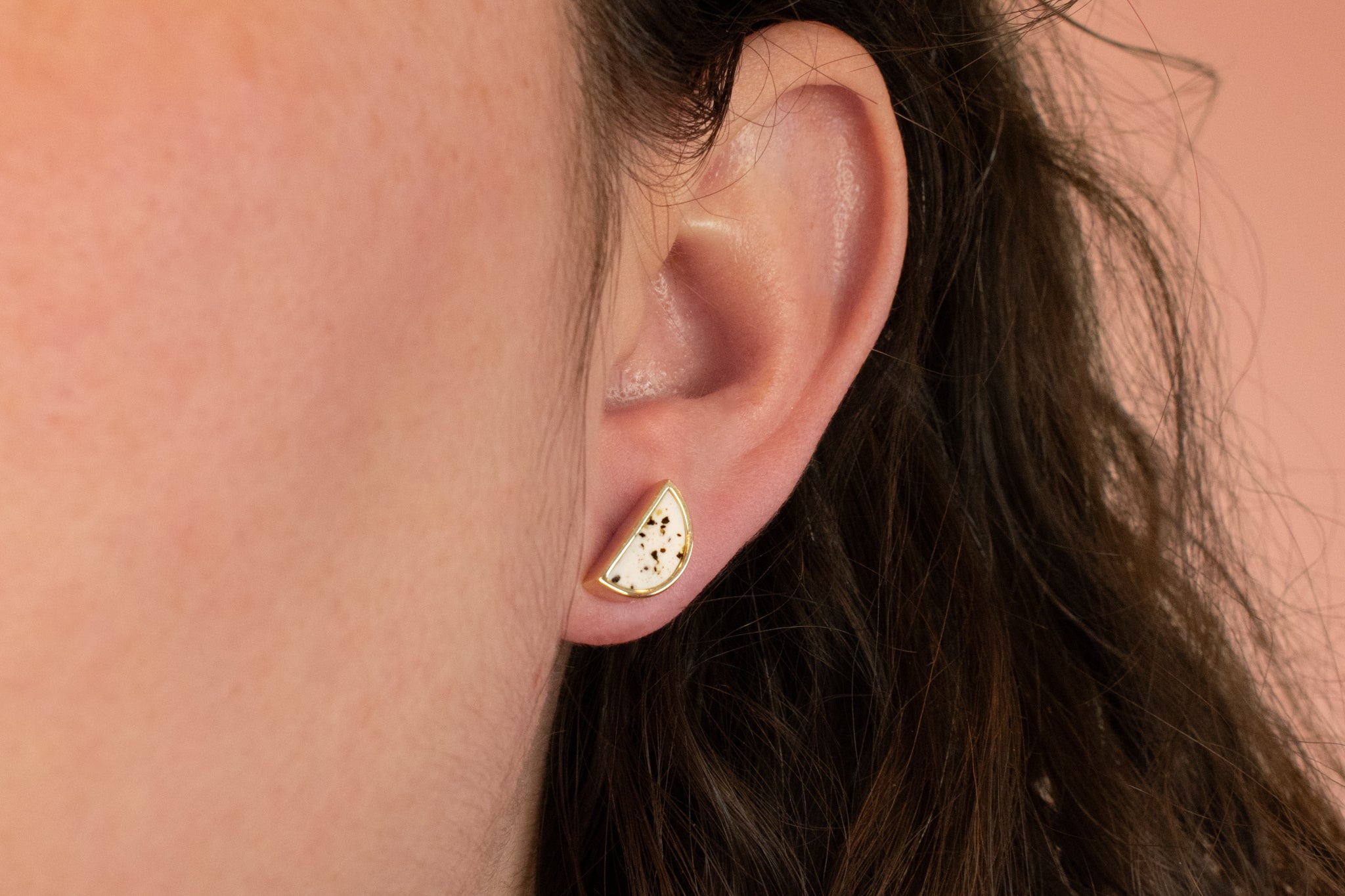 close up of models ear wearing modern moon earring in white terazzo