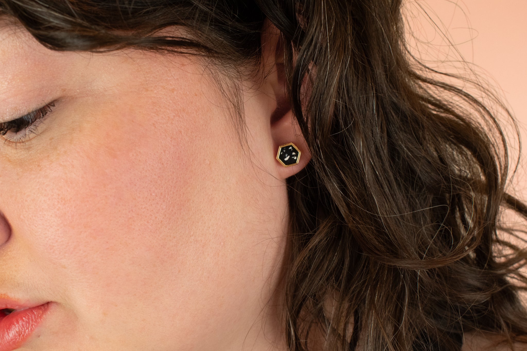 side profile of model wearing modern black and gold hexagon earring in terrazzo style