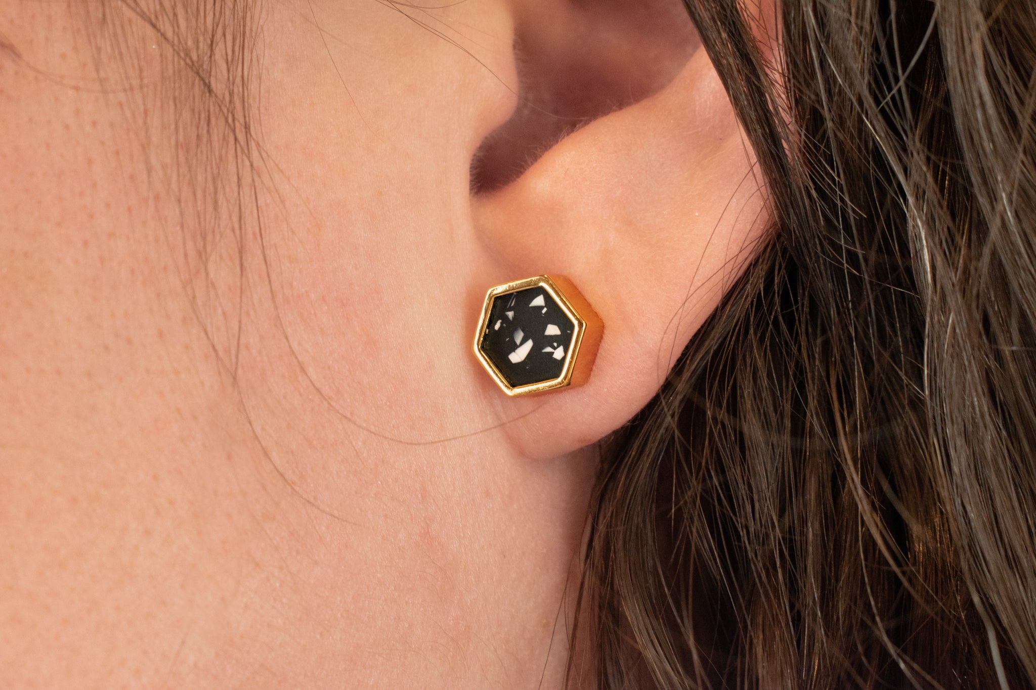 close up of models ear wearing black and white statement earring gold-plated hexagon shape