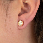 close of models ear with gold geometric earring in concrete design