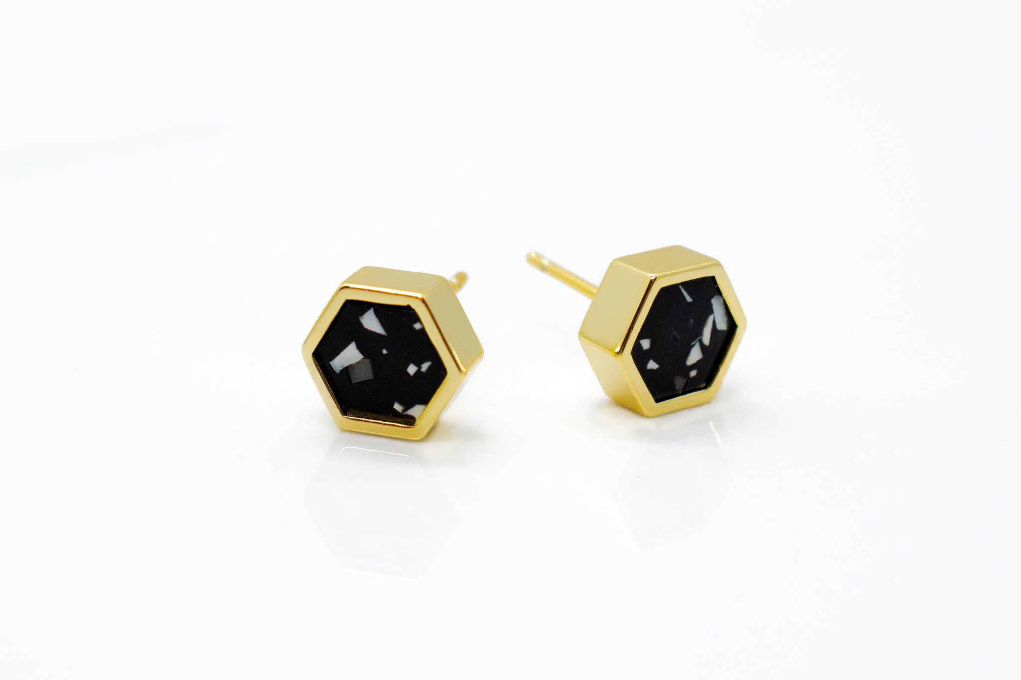 geometric gold plated hexagon everyday earrings in matte black clay with chips of white and granite clay 