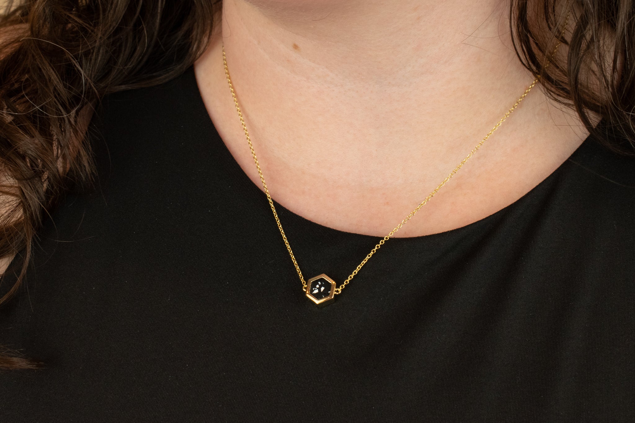 close up shot of model wearing adjustable 14k gold geometric necklace with matte black clay with flecks of white in terrazzo design